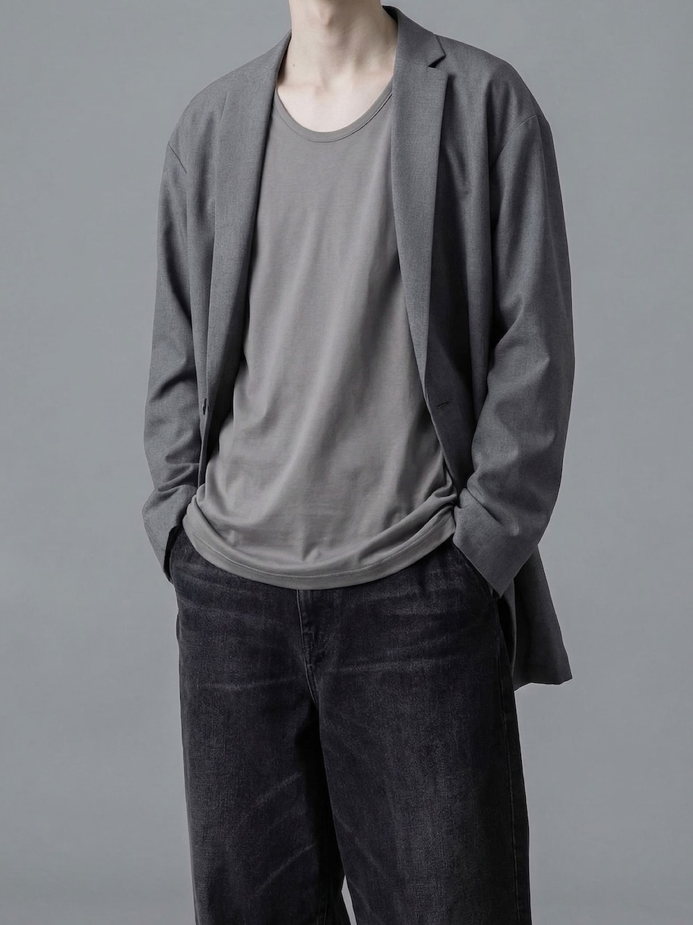 グレー系のテーラードジャケット、グレー系のTシャツ/カットソー、ブラック系のデニムパンツを着用したメンズの春コーディネートの2枚目の写真