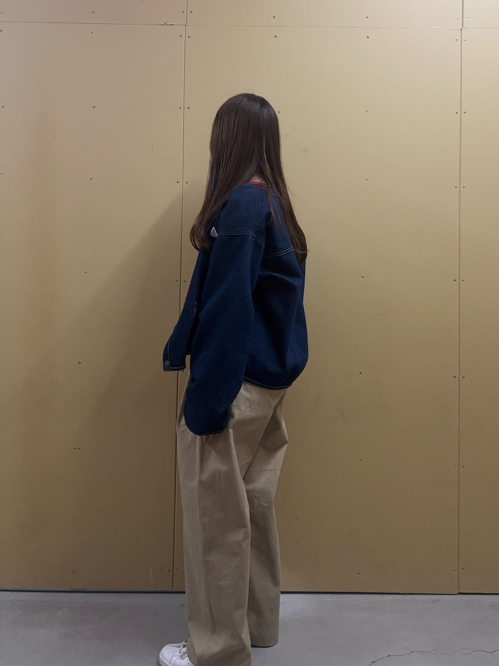 レッド系のニット/セーター、ブルー系のデニムジャケット、ベージュ系のチノパンツを着用したレディースの冬コーディネートの2枚目の写真