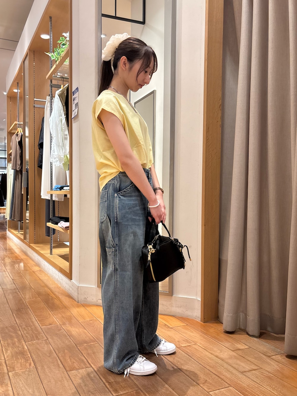 イエロー系のTシャツ/カットソー、ブルー系のデニムパンツ、ブラック系のショルダーバッグを着用したレディースの夏コーディネートの2枚目の写真