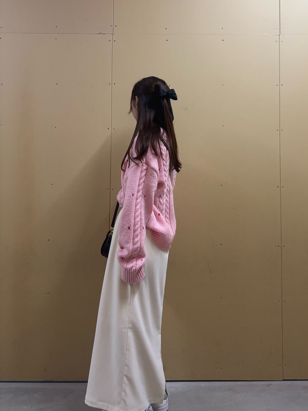 ピンク系のニット/セーター、ホワイト系のスカート、ブラック系のショルダーバッグを着用したレディースの秋コーディネートの2枚目の写真