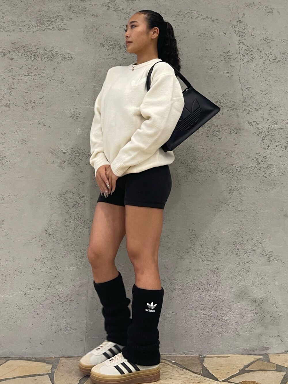 ブラック系のショルダーバッグ、ホワイト系のニット/セーター、ホワイト系のスニーカーを着用したレディースの秋コーディネートの2枚目の写真