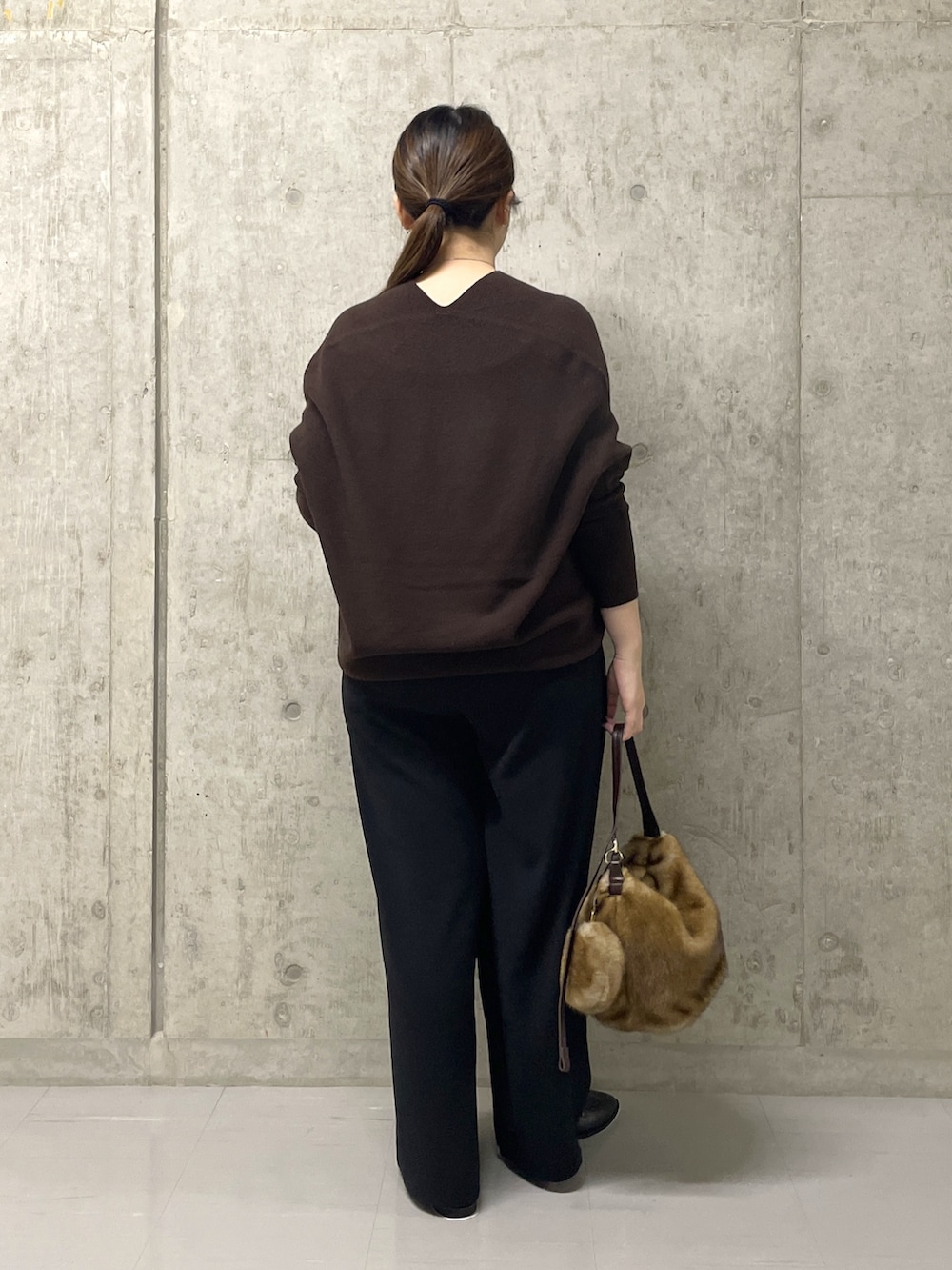 ブラウン系のニット/セーター、ブラック系のスラックス、イエロー系のハンドバッグを着用したレディースの秋コーディネートの4枚目の写真