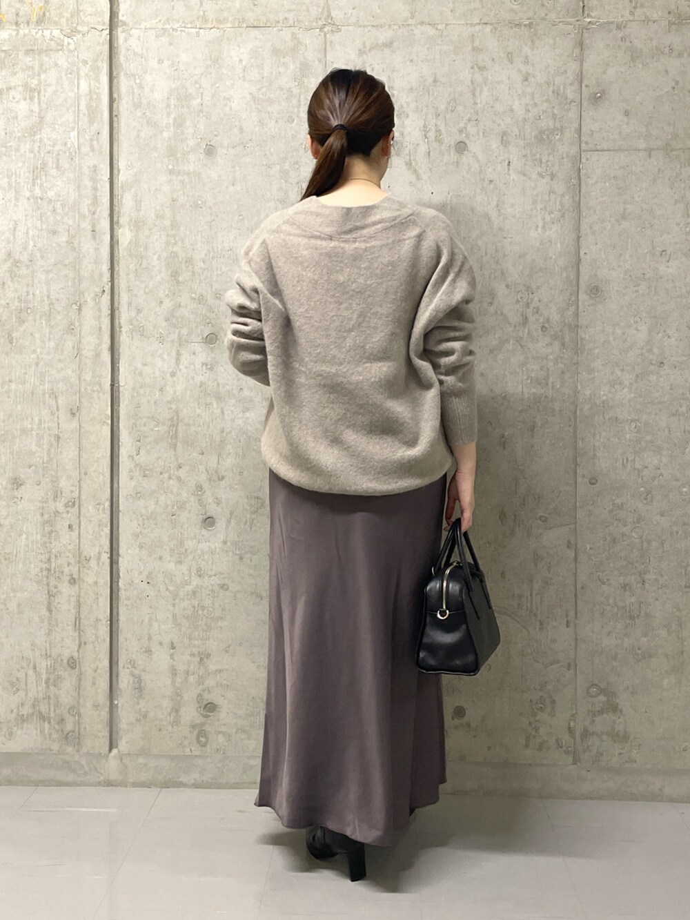 ブラウン系のスカート、ブラック系のボストンバッグ、ブラック系のブーツを着用したレディースの秋コーディネートの10枚目の写真