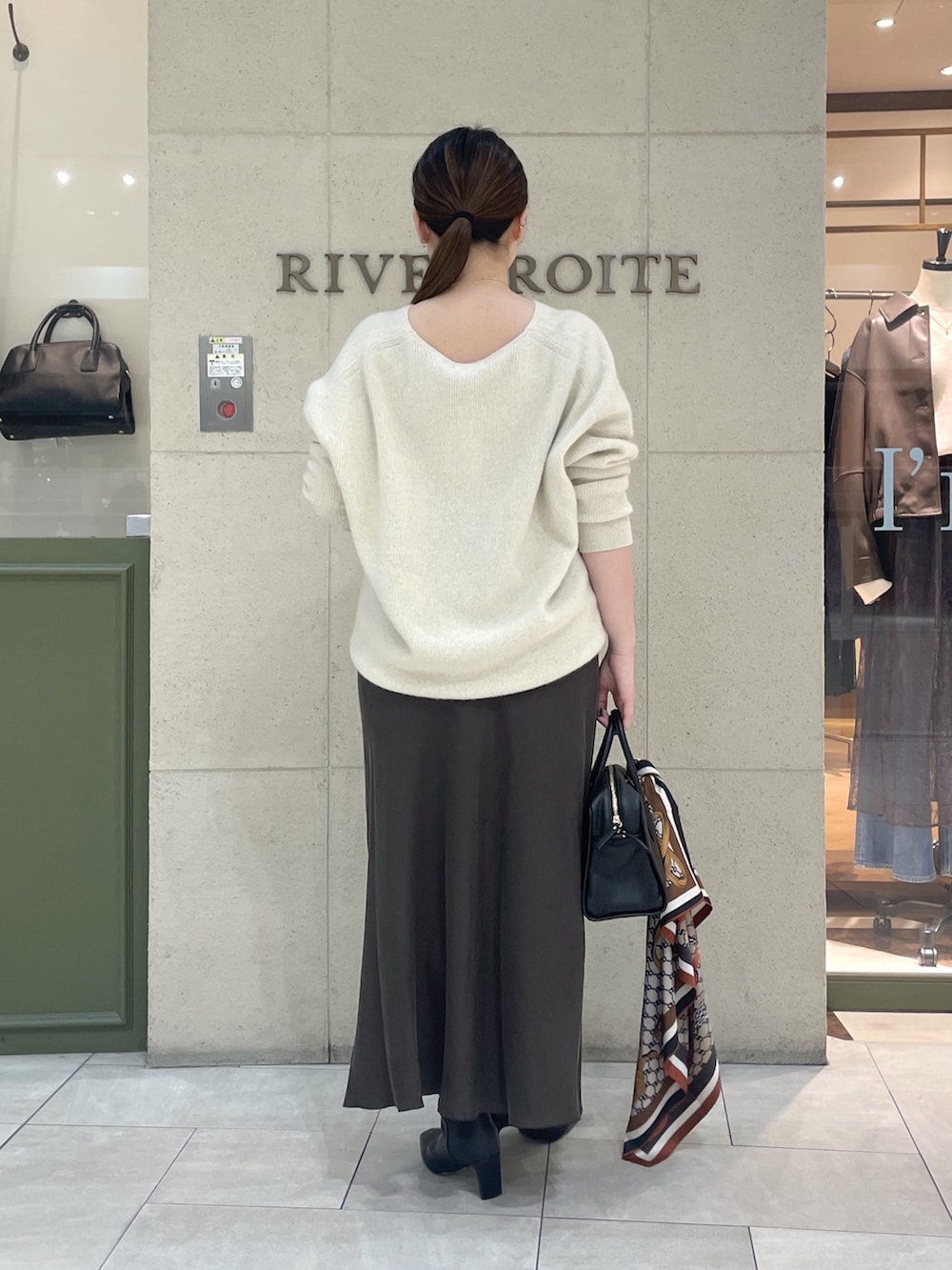 ベージュ系のニット/セーター、ブラウン系のスカート、ブラック系のボストンバッグを着用したレディースの秋コーディネートの4枚目の写真