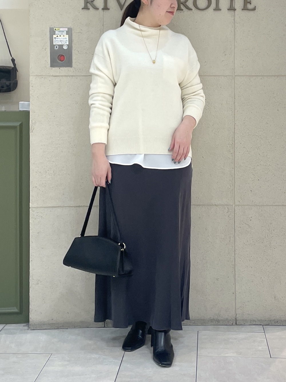 ホワイト系のニット/セーター、ホワイト系のシャツ/ブラウス、ブラック系のブーツを着用したレディースの冬コーディネートの2枚目の写真