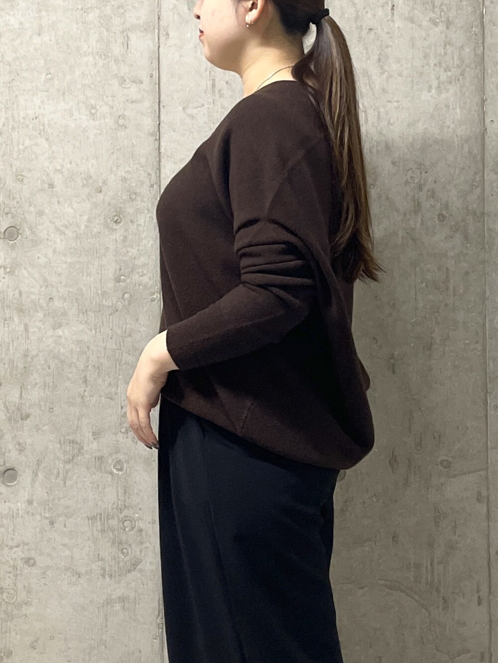 ブラウン系のニット/セーター、ブラック系のスラックス、イエロー系のハンドバッグを着用したレディースの秋コーディネートの6枚目の写真