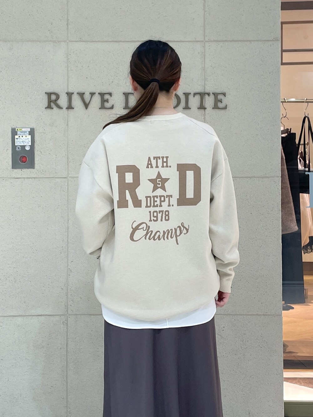 ホワイト系のニット/セーター、ホワイト系のTシャツ/カットソー、ブラウン系のスカートを着用したレディースの秋コーディネートの7枚目の写真