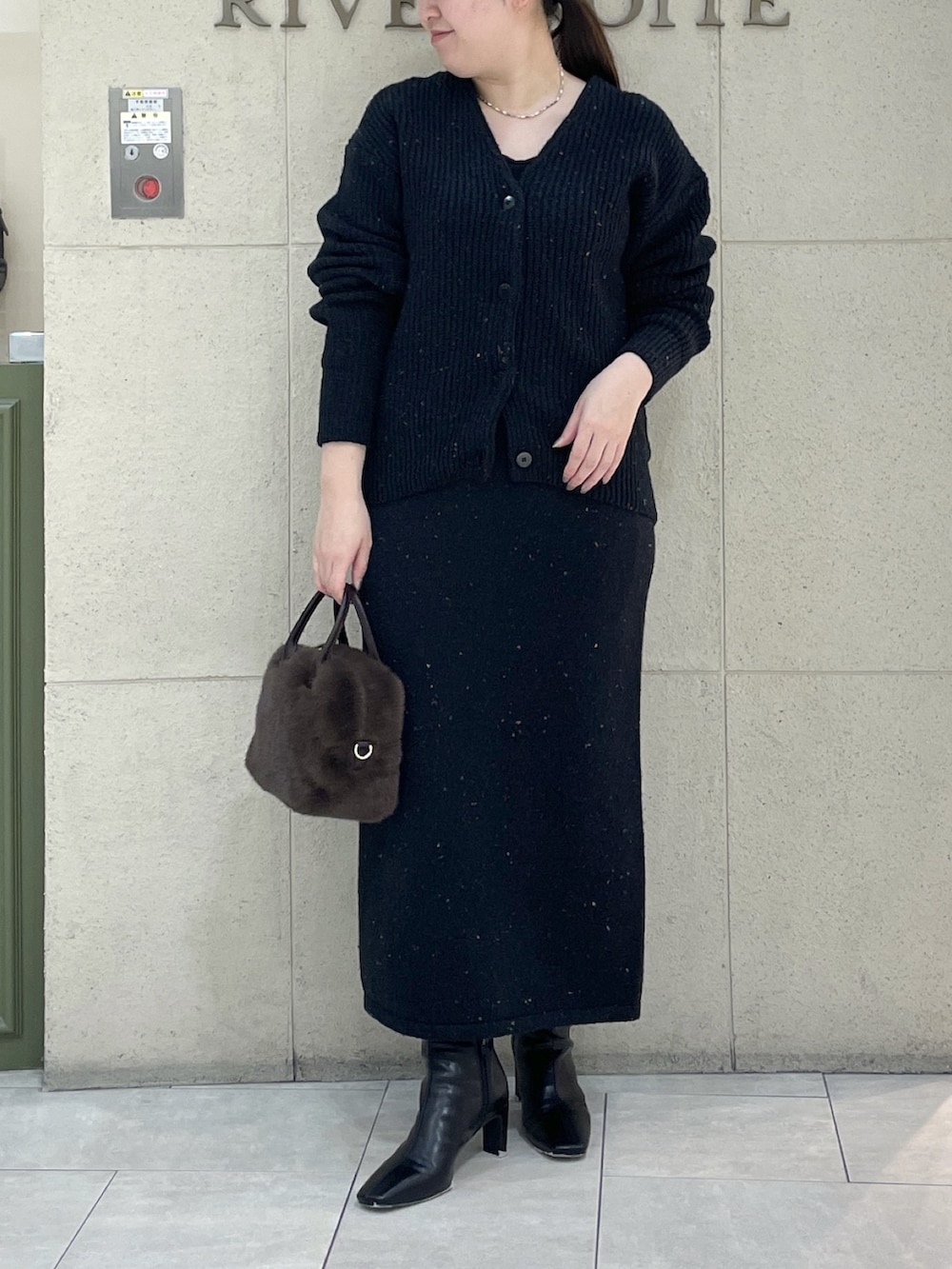 ブラック系のカーディガン/ボレロ、ブラック系のスカート、ブラウン系のボストンバッグを着用したレディースの秋コーディネートの2枚目の写真