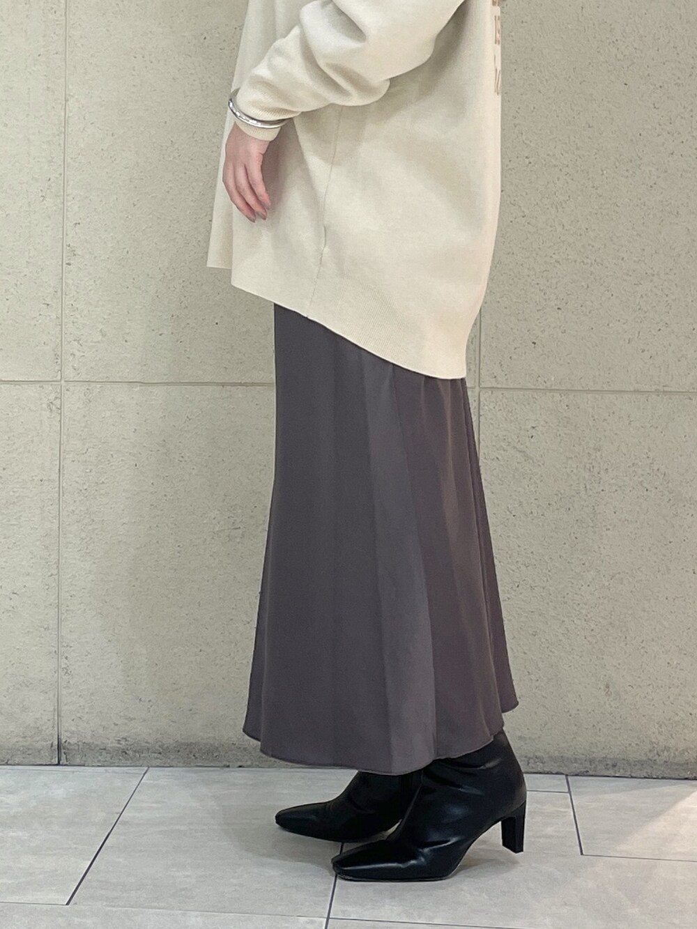 ホワイト系のニット/セーター、ホワイト系のTシャツ/カットソー、ブラウン系のスカートを着用したレディースの秋コーディネートの9枚目の写真