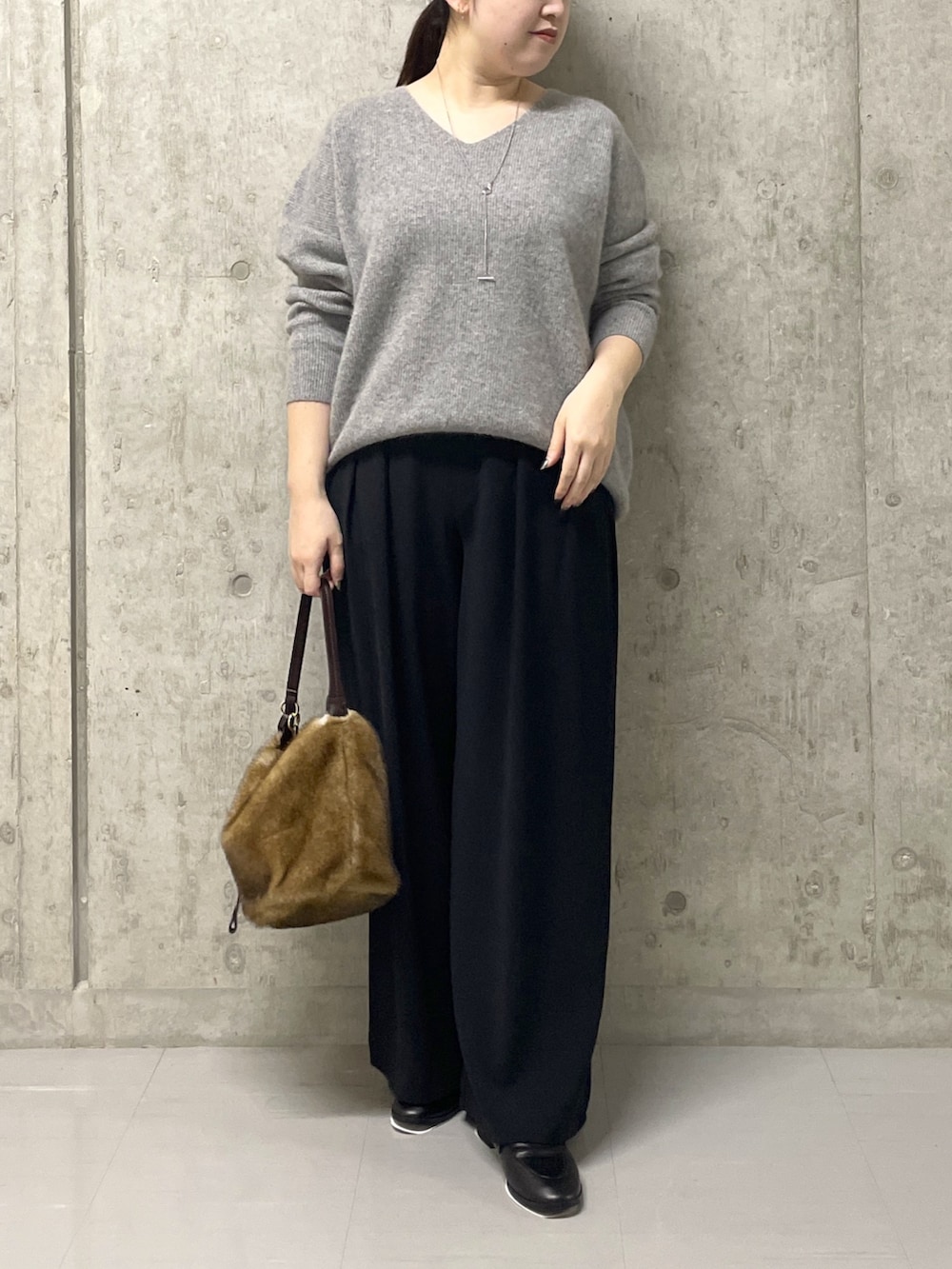 ブラック系のスラックス、グレー系のニット/セーター、ブラック系のローファーを着用したレディースの秋コーディネートの2枚目の写真