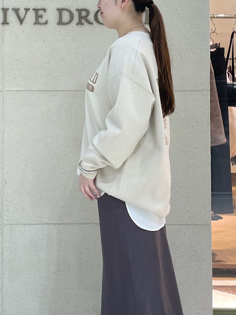 ホワイト系のニット/セーター、ホワイト系のTシャツ/カットソー、ブラウン系のスカートを着用したレディースの秋コーディネートの6枚目の写真