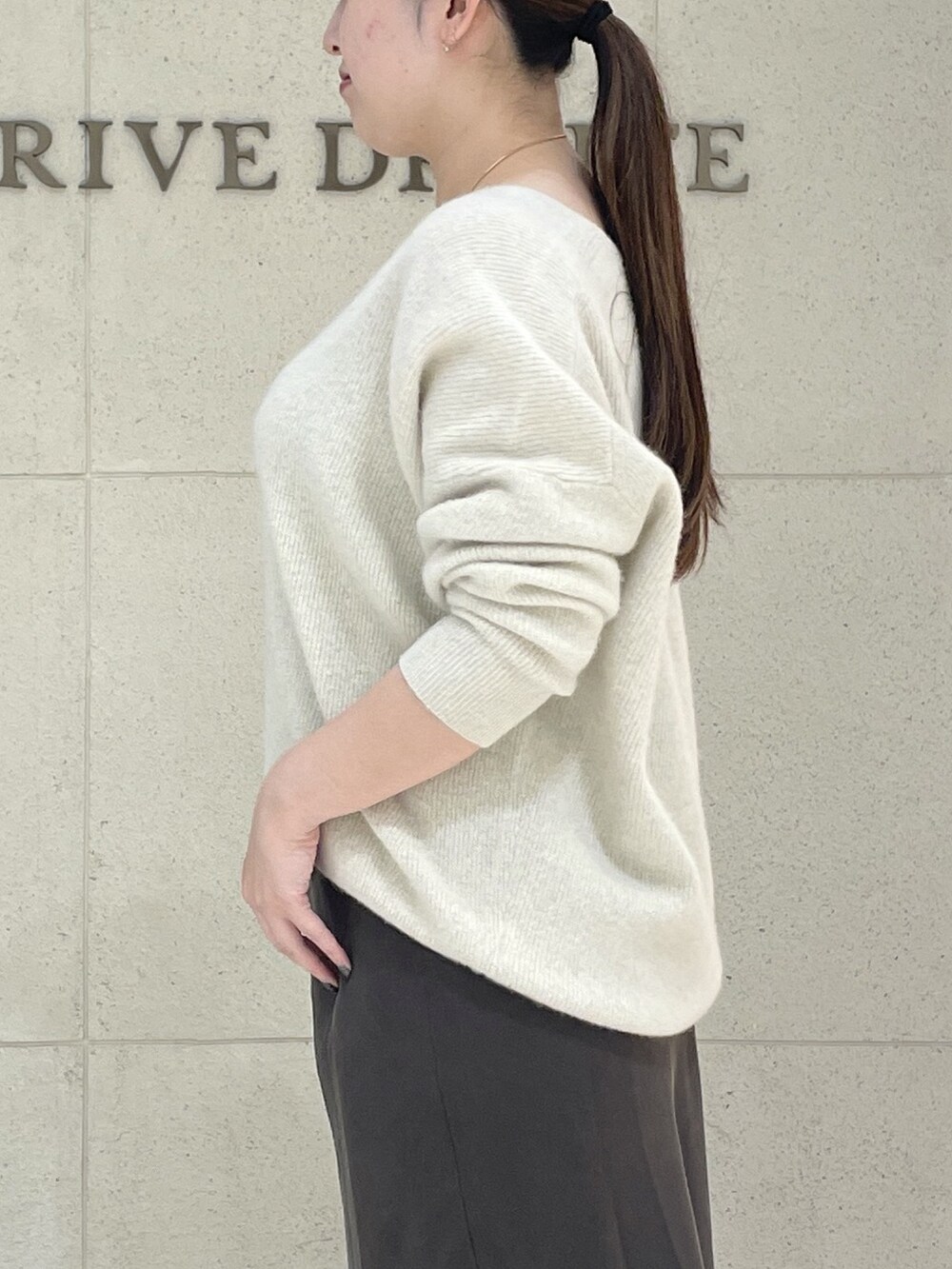 ベージュ系のニット/セーター、ブラウン系のスカート、ブラック系のボストンバッグを着用したレディースの秋コーディネートの6枚目の写真