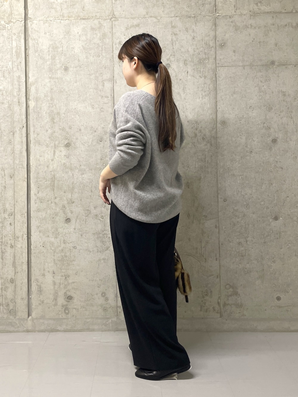 ブラック系のスラックス、グレー系のニット/セーター、ブラック系のローファーを着用したレディースの秋コーディネートの3枚目の写真