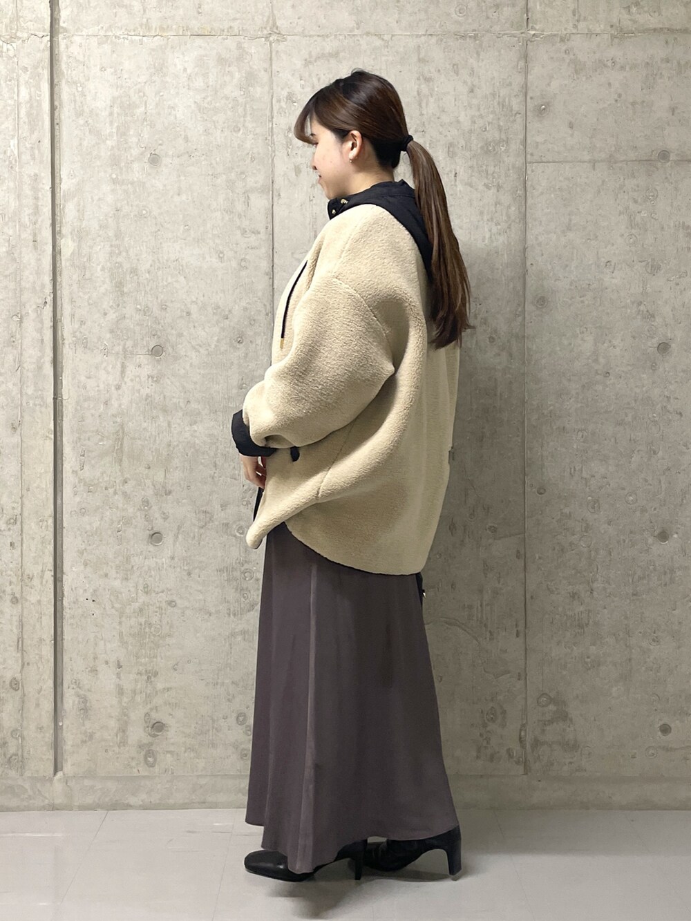 ブラウン系のスカート、ブラック系のボストンバッグ、ブラック系のブーツを着用したレディースの秋コーディネートの4枚目の写真