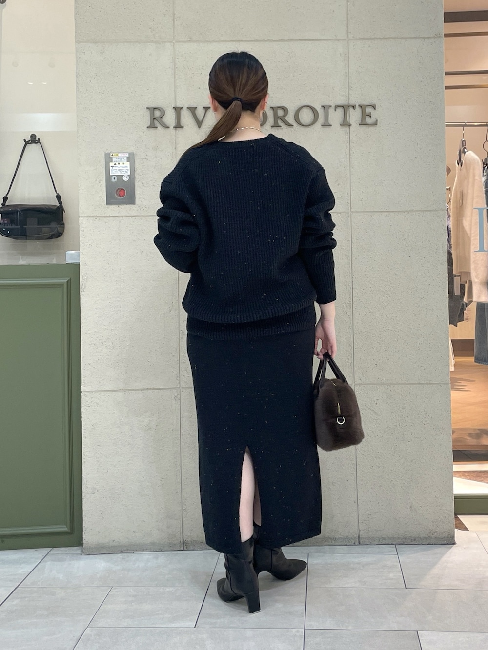 ブラック系のカーディガン/ボレロ、ブラック系のスカート、ブラウン系のボストンバッグを着用したレディースの秋コーディネートの4枚目の写真