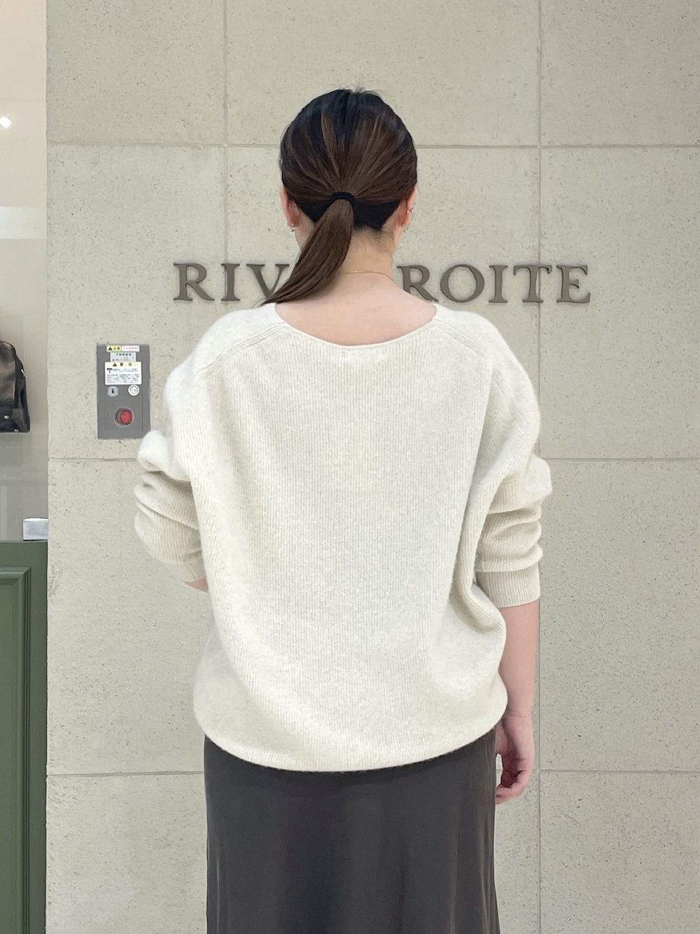 ベージュ系のニット/セーター、ブラウン系のスカート、ブラック系のボストンバッグを着用したレディースの秋コーディネートの7枚目の写真