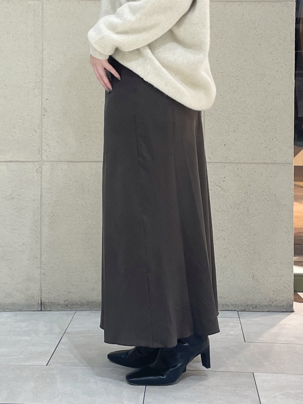 ベージュ系のニット/セーター、ブラウン系のスカート、ブラック系のボストンバッグを着用したレディースの秋コーディネートの9枚目の写真