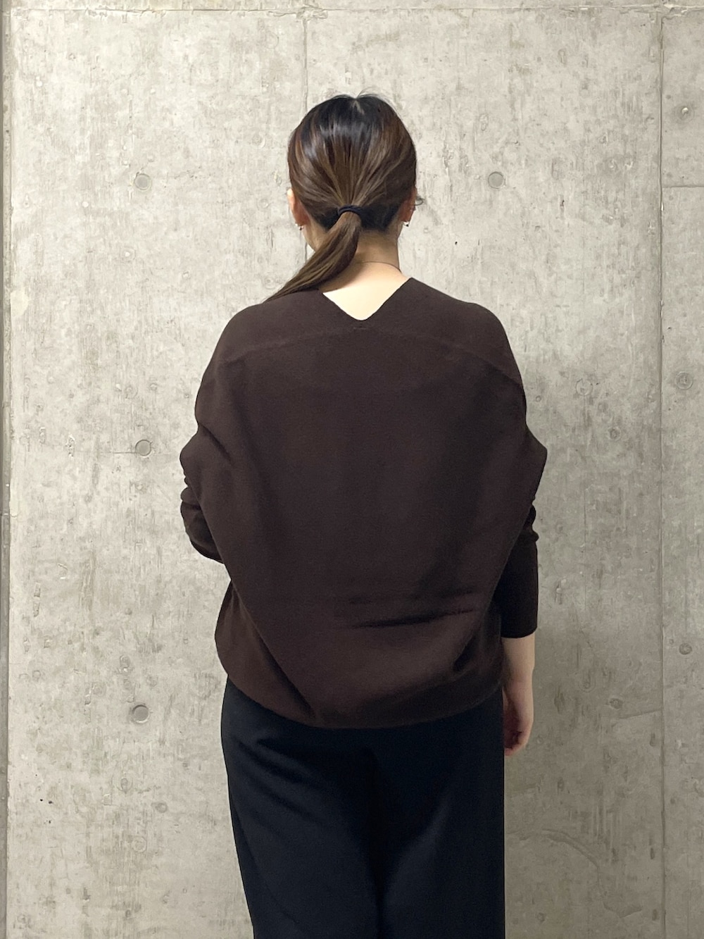 ブラウン系のニット/セーター、ブラック系のスラックス、イエロー系のハンドバッグを着用したレディースの秋コーディネートの7枚目の写真