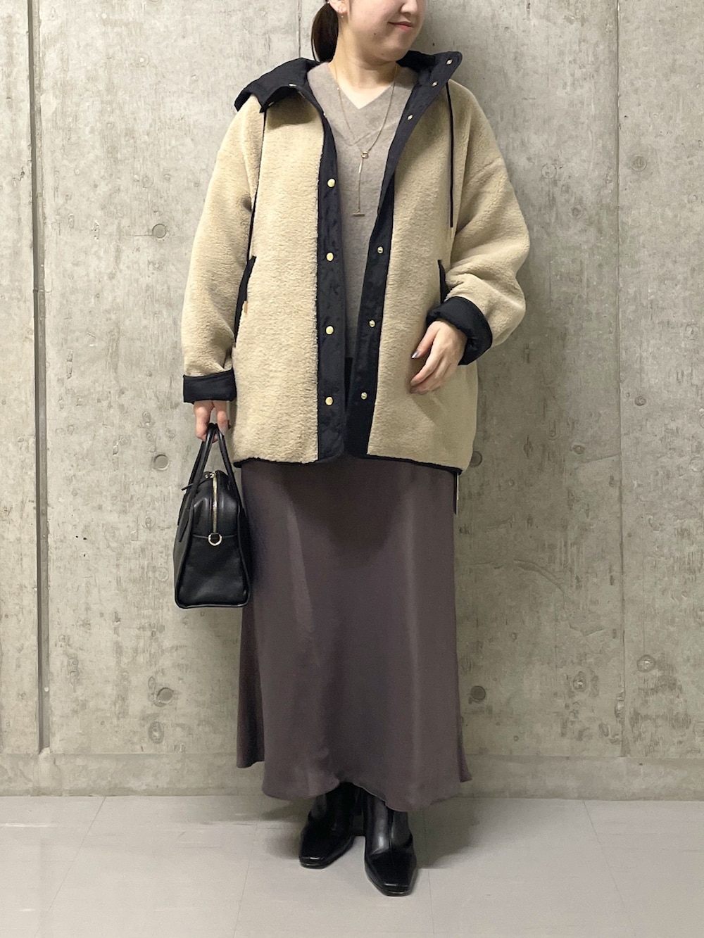 ブラウン系のスカート、ブラック系のボストンバッグ、ブラック系のブーツを着用したレディースの秋コーディネートの2枚目の写真