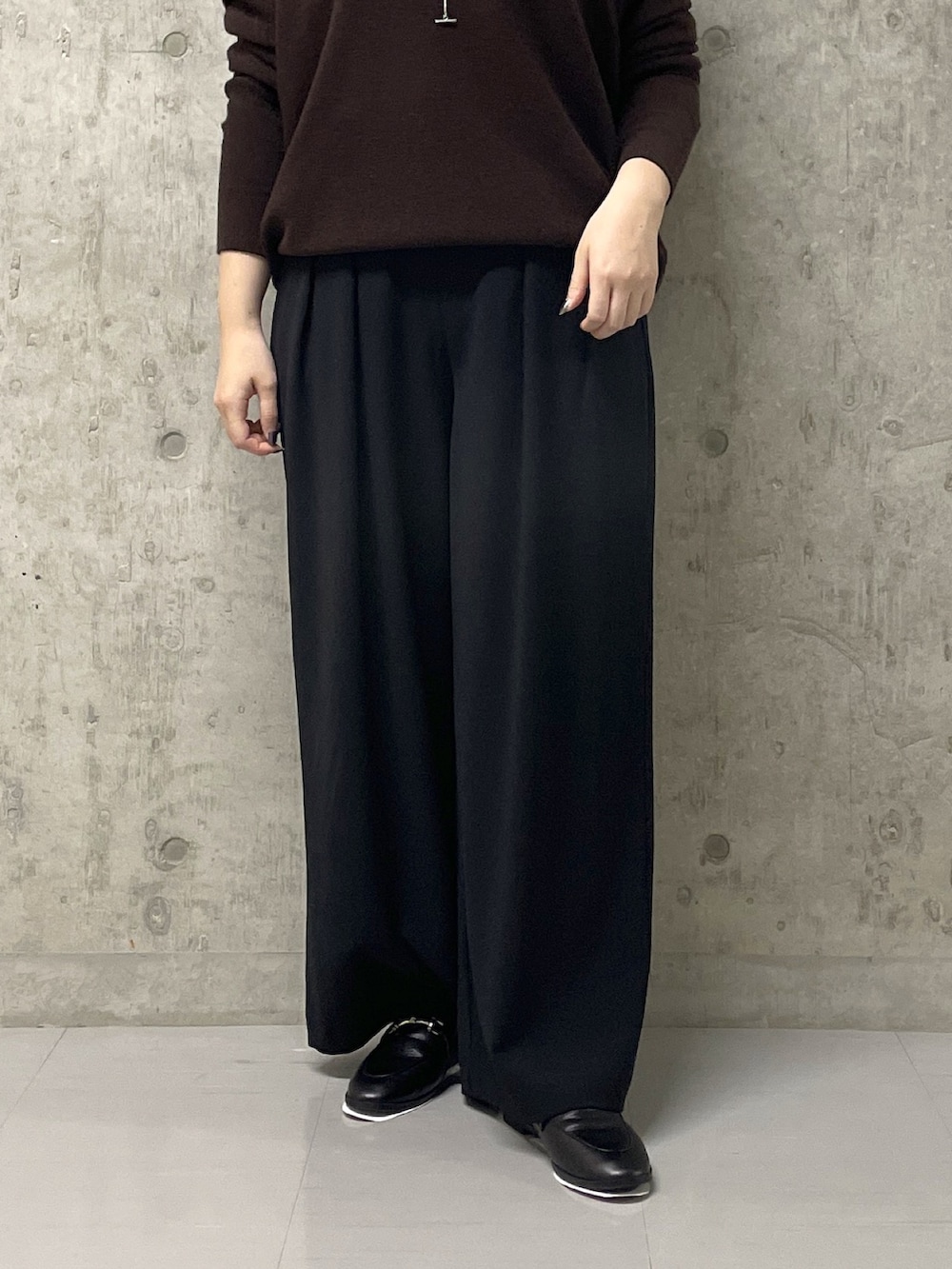 ブラウン系のニット/セーター、ブラック系のスラックス、イエロー系のハンドバッグを着用したレディースの秋コーディネートの8枚目の写真