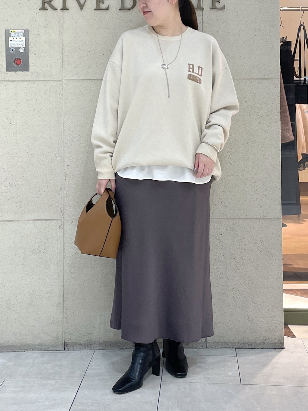 ホワイト系のニット/セーター、ホワイト系のTシャツ/カットソー、ブラウン系のスカートを着用したレディースの秋コーディネートの2枚目の写真