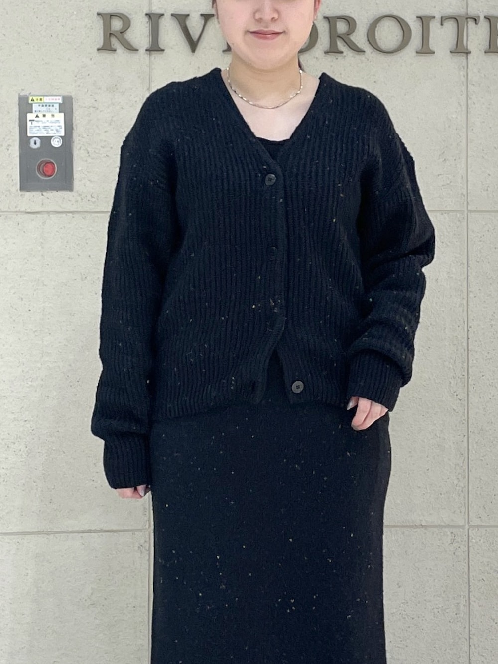 ブラック系のカーディガン/ボレロ、ブラック系のスカート、ブラウン系のボストンバッグを着用したレディースの秋コーディネートの5枚目の写真