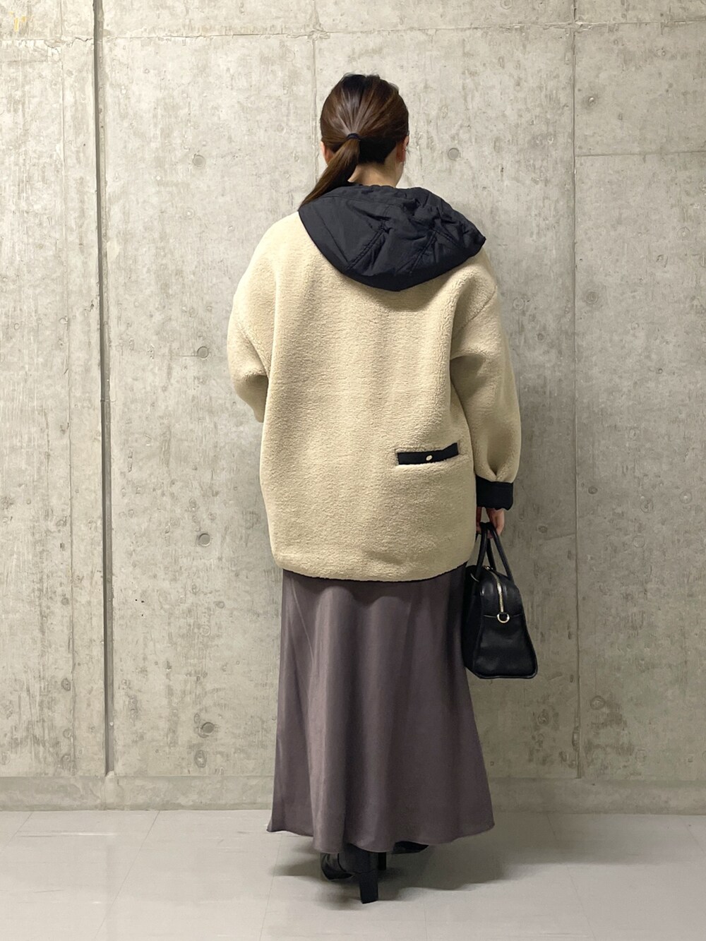 ブラウン系のスカート、ブラック系のボストンバッグ、ブラック系のブーツを着用したレディースの秋コーディネートの3枚目の写真