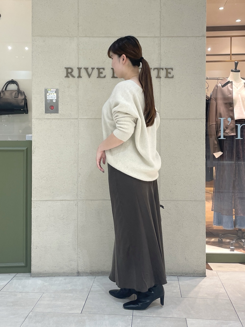 ベージュ系のニット/セーター、ブラウン系のスカート、ブラック系のボストンバッグを着用したレディースの秋コーディネートの3枚目の写真