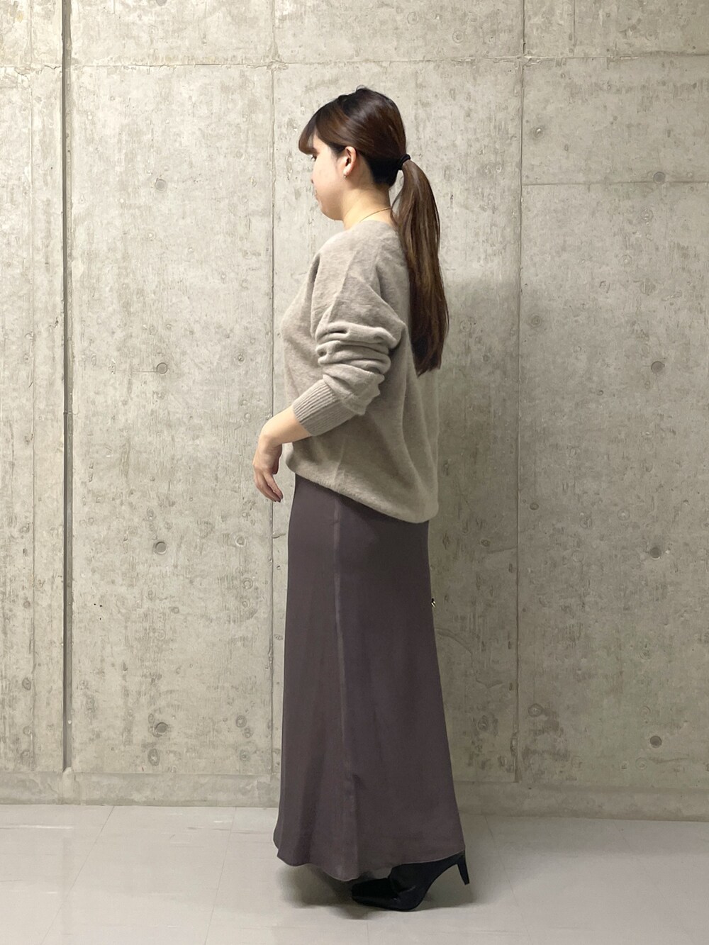 ブラウン系のスカート、ブラック系のボストンバッグ、ブラック系のブーツを着用したレディースの秋コーディネートの9枚目の写真