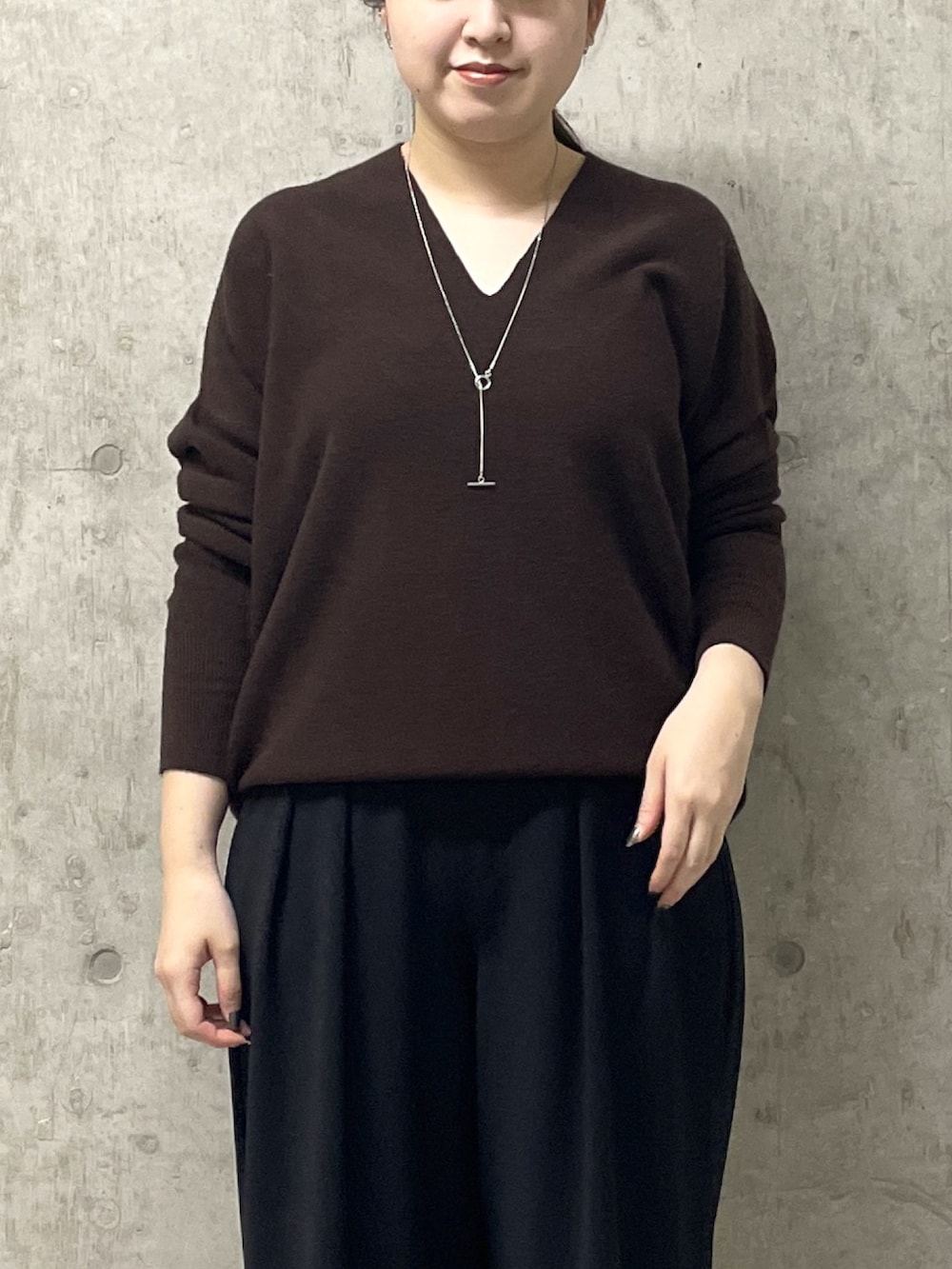 ブラウン系のニット/セーター、ブラック系のスラックス、イエロー系のハンドバッグを着用したレディースの秋コーディネートの5枚目の写真