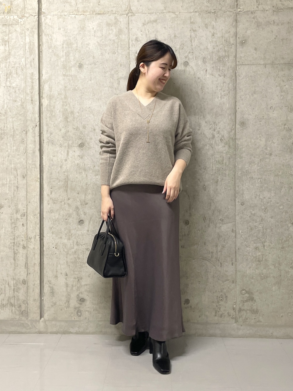 ブラウン系のスカート、ブラック系のボストンバッグ、ブラック系のブーツを着用したレディースの秋コーディネートの8枚目の写真