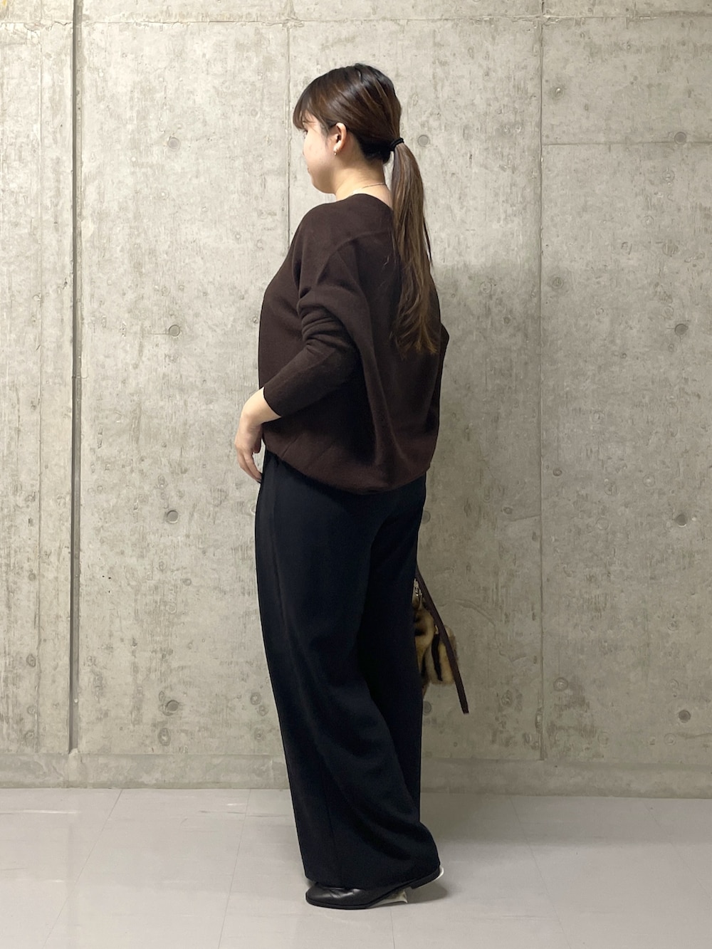 ブラウン系のニット/セーター、ブラック系のスラックス、イエロー系のハンドバッグを着用したレディースの秋コーディネートの3枚目の写真