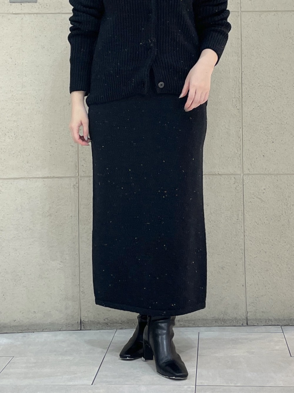 ブラック系のカーディガン/ボレロ、ブラック系のスカート、ブラウン系のボストンバッグを着用したレディースの秋コーディネートの7枚目の写真