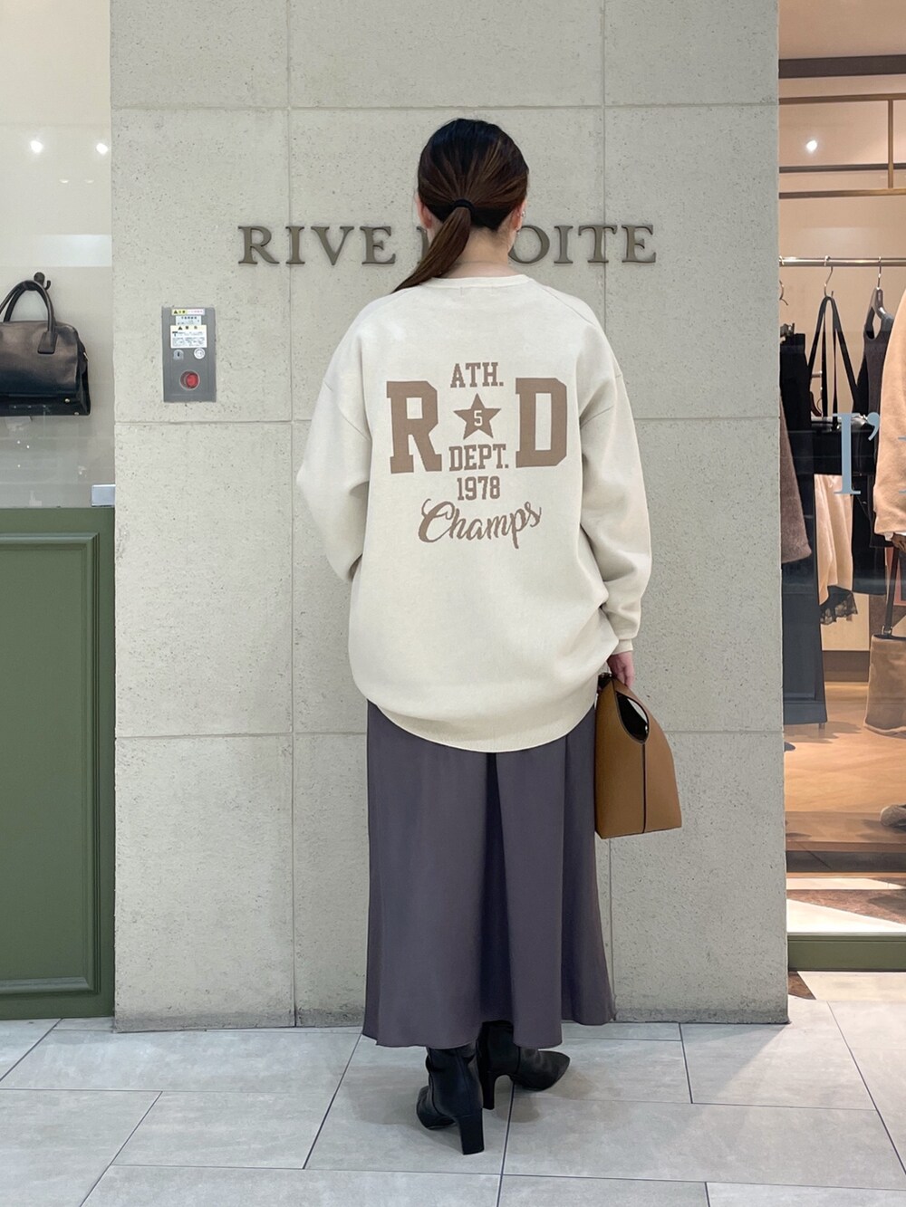 ホワイト系のニット/セーター、ホワイト系のTシャツ/カットソー、ブラウン系のスカートを着用したレディースの秋コーディネートの4枚目の写真