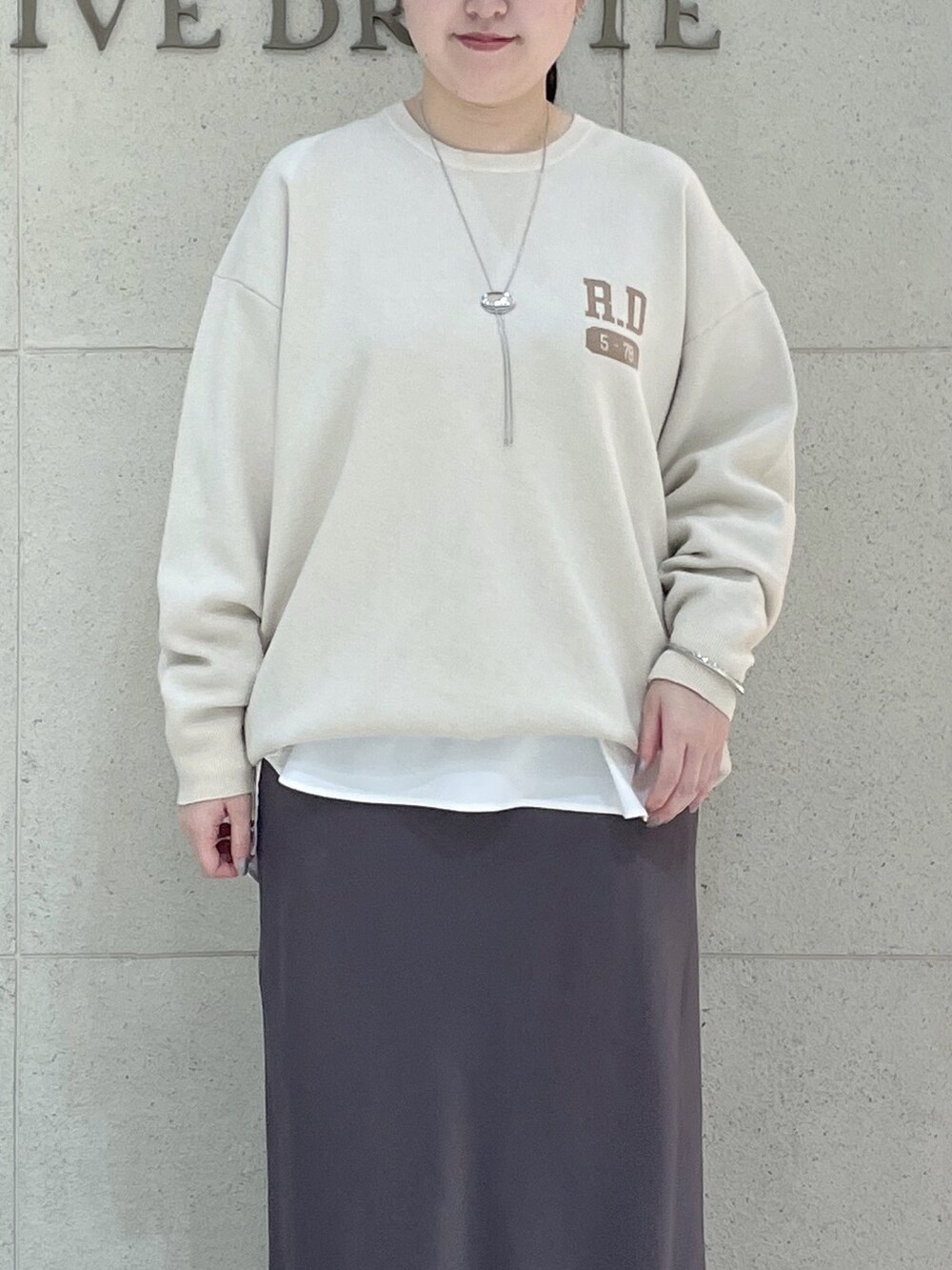 ホワイト系のニット/セーター、ホワイト系のTシャツ/カットソー、ブラウン系のスカートを着用したレディースの秋コーディネートの5枚目の写真