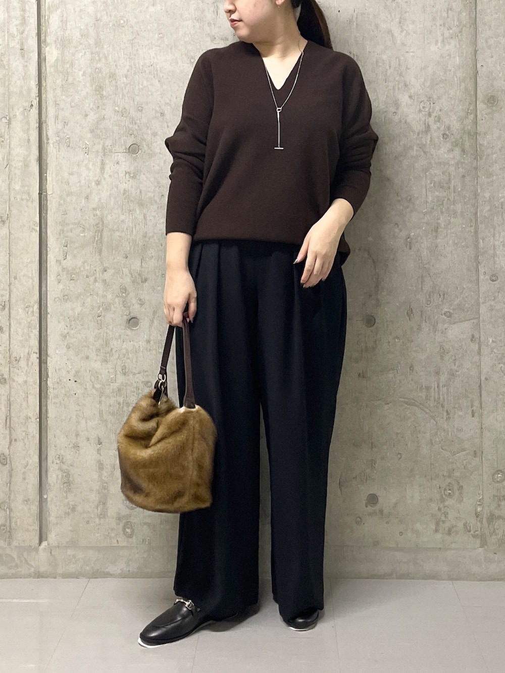 ブラウン系のニット/セーター、ブラック系のスラックス、イエロー系のハンドバッグを着用したレディースの秋コーディネートの2枚目の写真