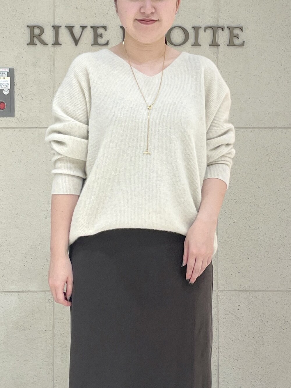 ベージュ系のニット/セーター、ブラウン系のスカート、ブラック系のボストンバッグを着用したレディースの秋コーディネートの5枚目の写真