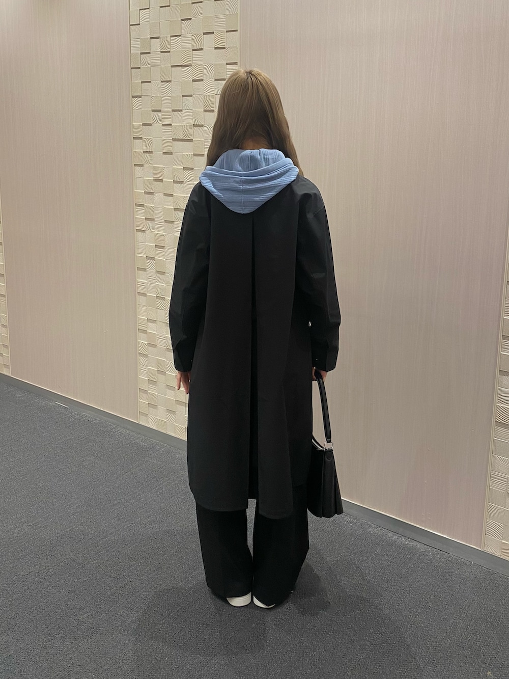 ブルー系のパーカー、ブラック系のステンカラーコート、ブラック系のスラックスを着用したレディースの冬コーディネートの4枚目の写真