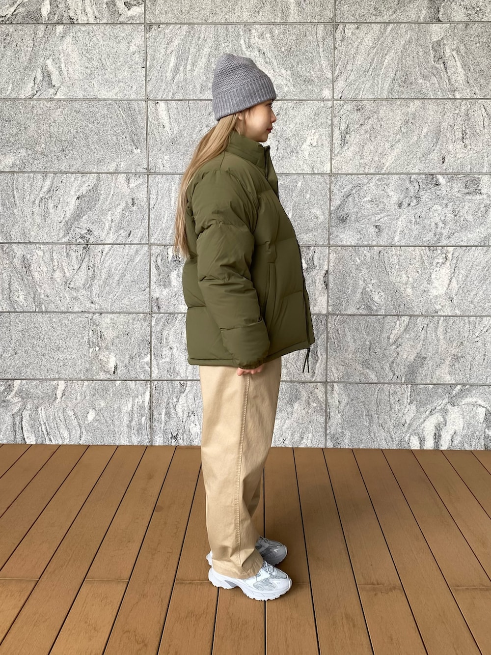 グリーン系のダウンジャケット/コート、ブルー系のニット/セーター、ベージュ系のチノパンツを着用したレディースの冬コーディネートの2枚目の写真