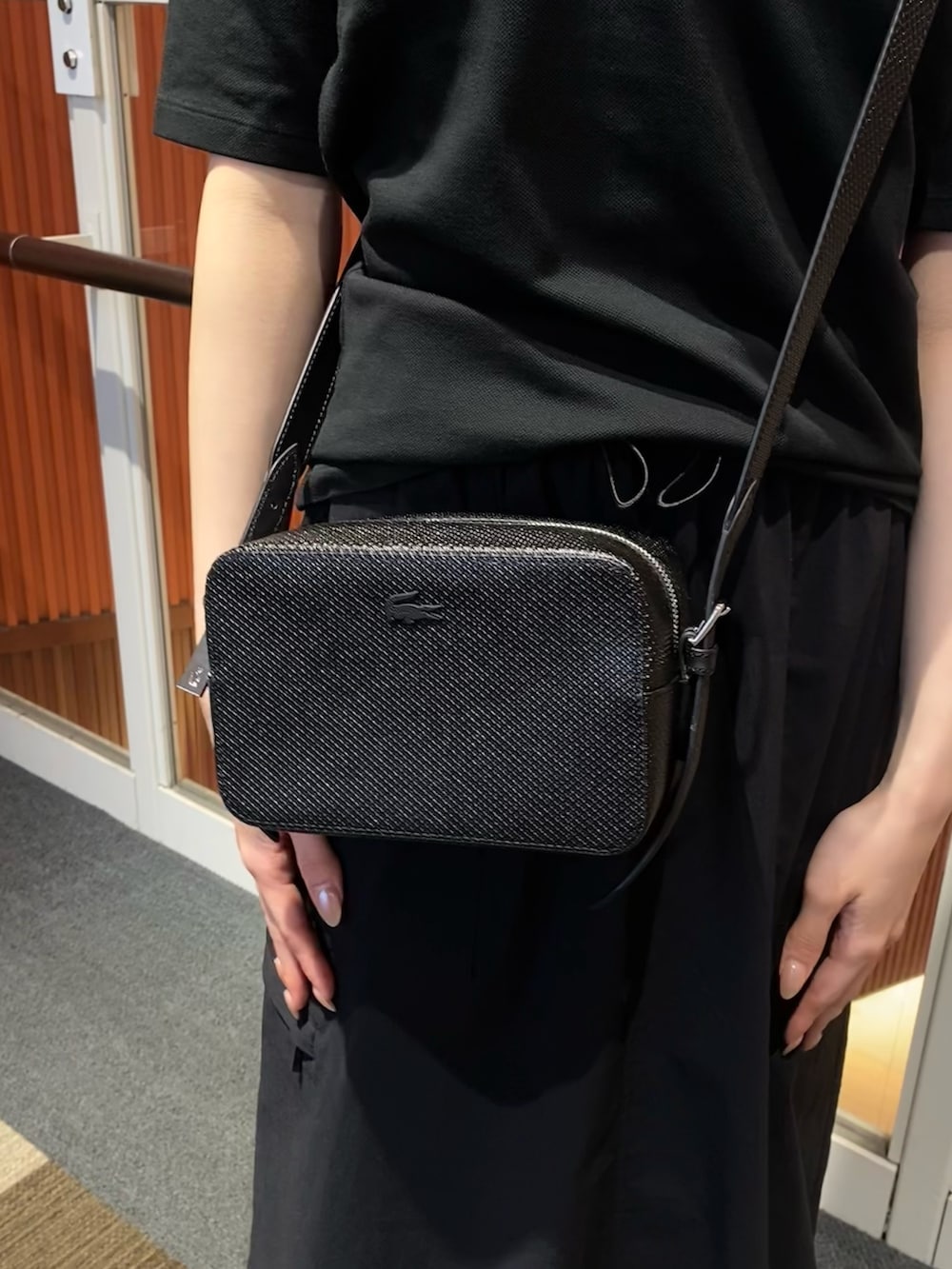 ブラック系のスカート、ブラック系のポロシャツ、ブラック系のサンダルを着用したレディースの夏コーディネートの5枚目の写真