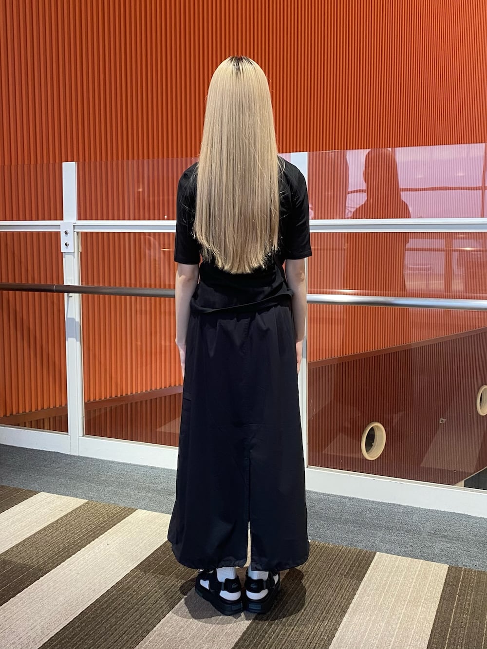 ブラック系のスカート、ブラック系のポロシャツ、ブラック系のサンダルを着用したレディースの夏コーディネートの3枚目の写真
