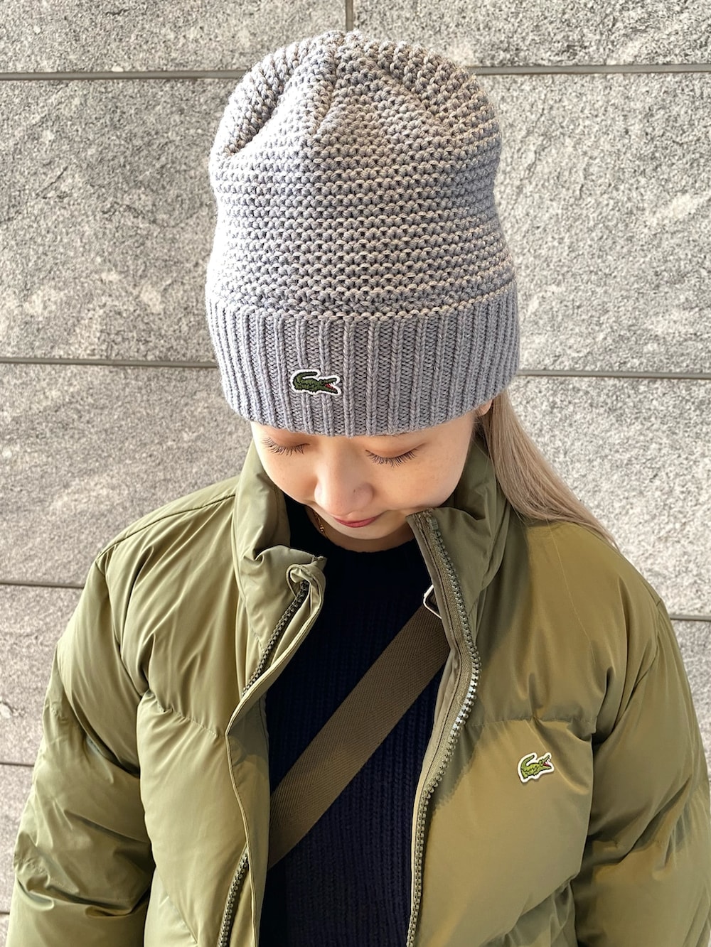 グリーン系のダウンジャケット/コート、ブルー系のニット/セーター、ベージュ系のチノパンツを着用したレディースの冬コーディネートの8枚目の写真