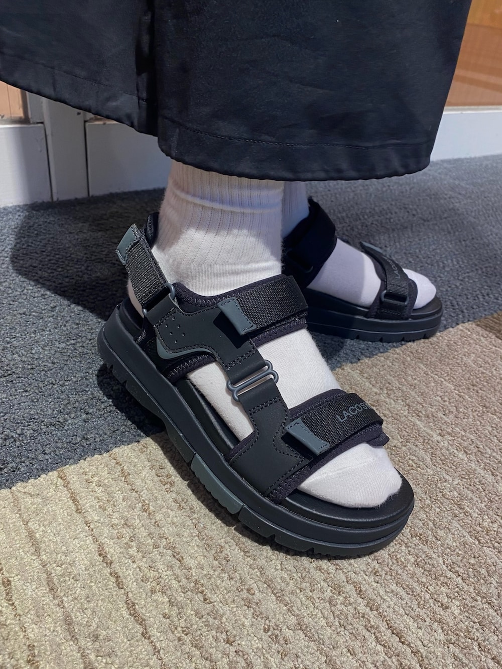 ブラック系のスカート、ブラック系のポロシャツ、ブラック系のサンダルを着用したレディースの夏コーディネートの6枚目の写真