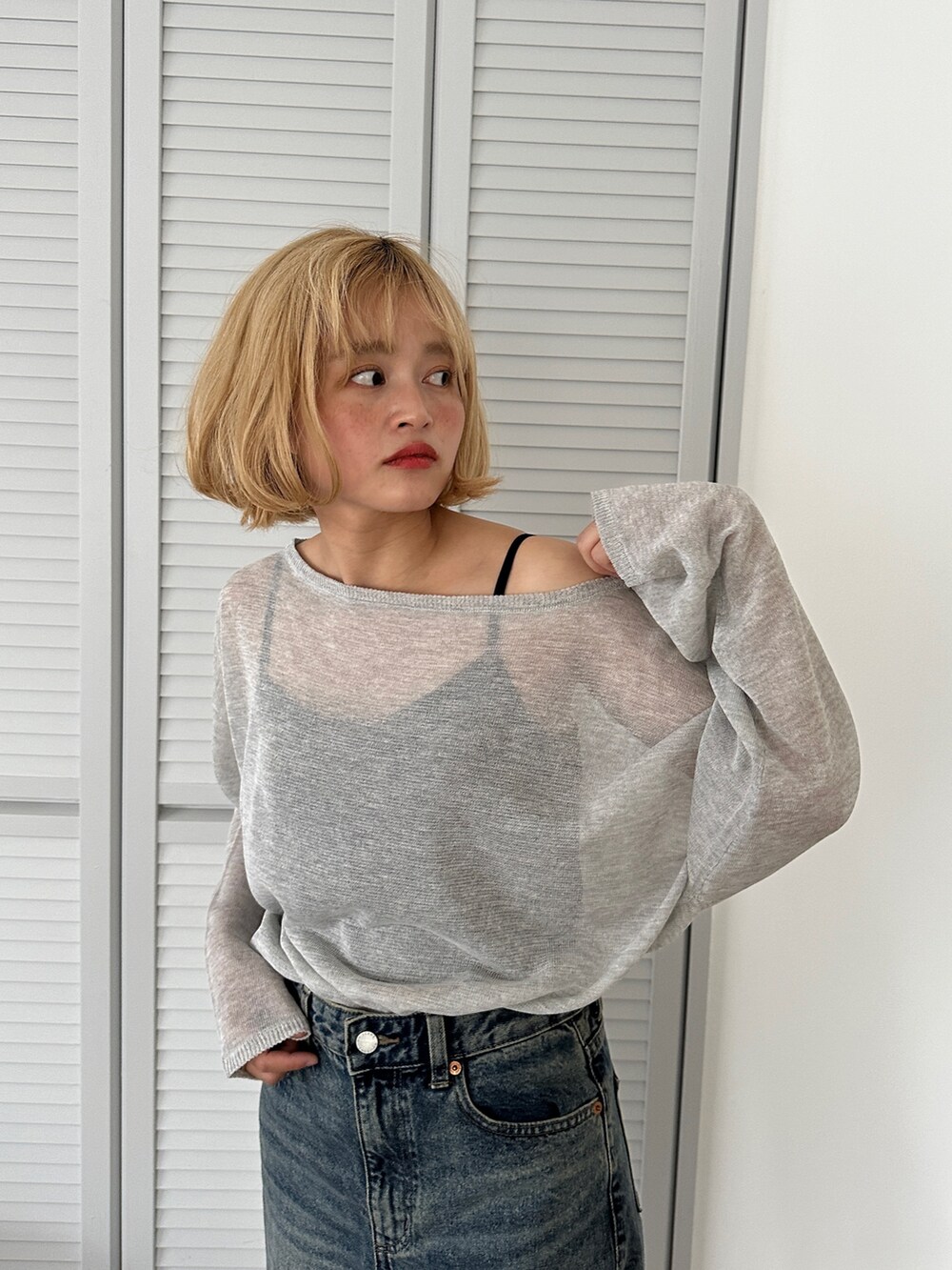グレー系のニット/セーター、ブルー系のデニムパンツを着用したレディースの春コーディネートの2枚目の写真
