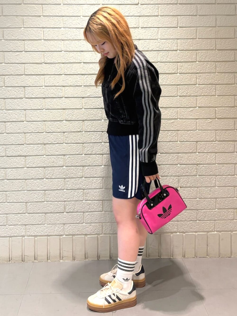 ホワイト系のスニーカー、ブラック系のデニムジャケット、ブルー系のスウェットパンツを着用したレディースの夏コーディネートの2枚目の写真