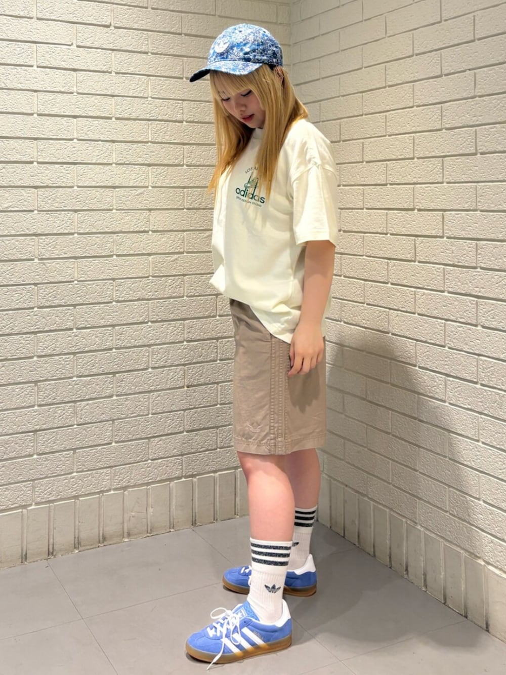 ホワイト系のTシャツ/カットソー、グリーン系のパンツ、ブルー系のスニーカーを着用したレディースの春コーディネートの2枚目の写真