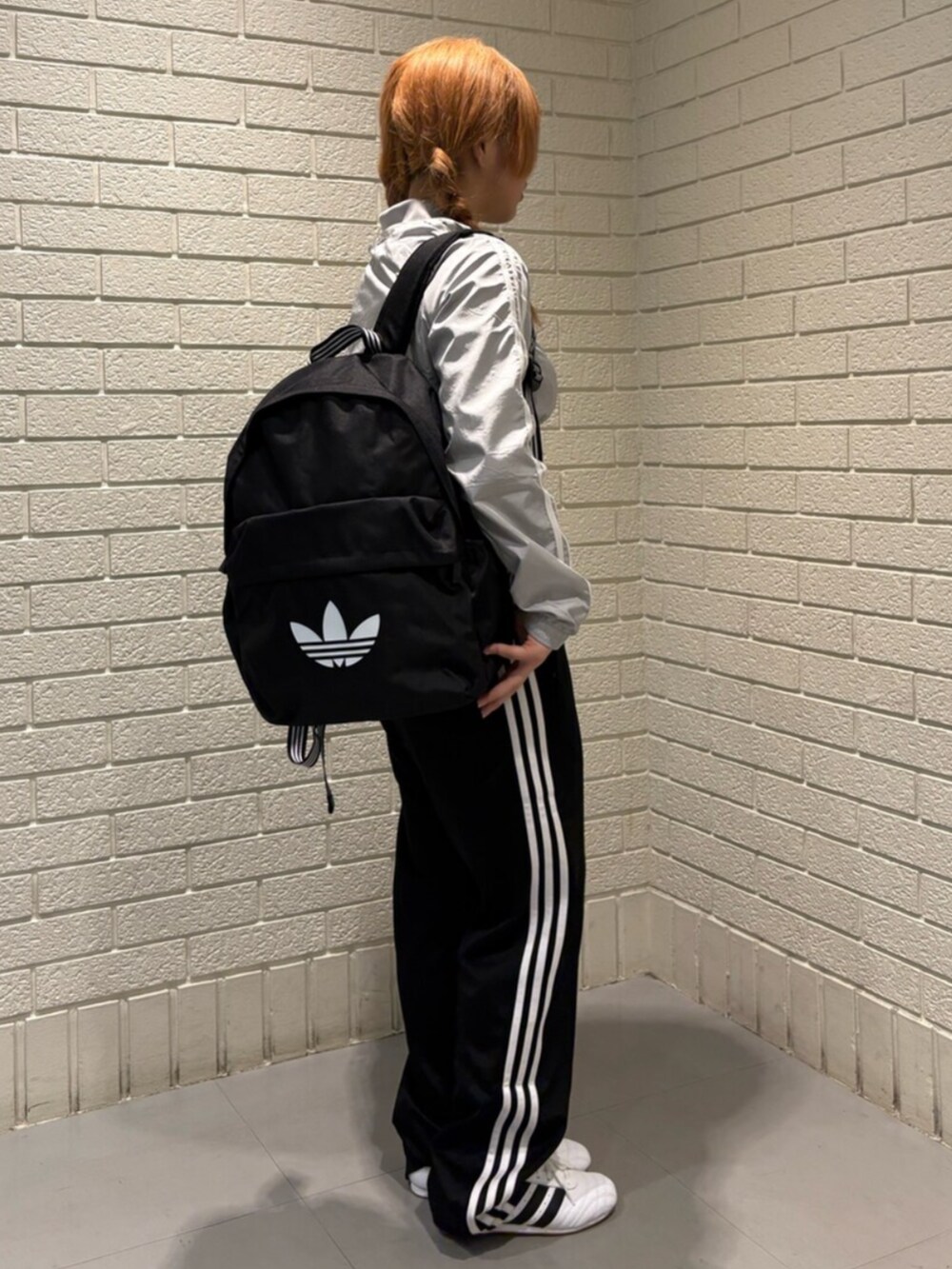 グレー系のナイロンジャケット、ブラック系のスウェットパンツ、ホワイト系のスニーカーを着用したレディースの夏コーディネートの2枚目の写真