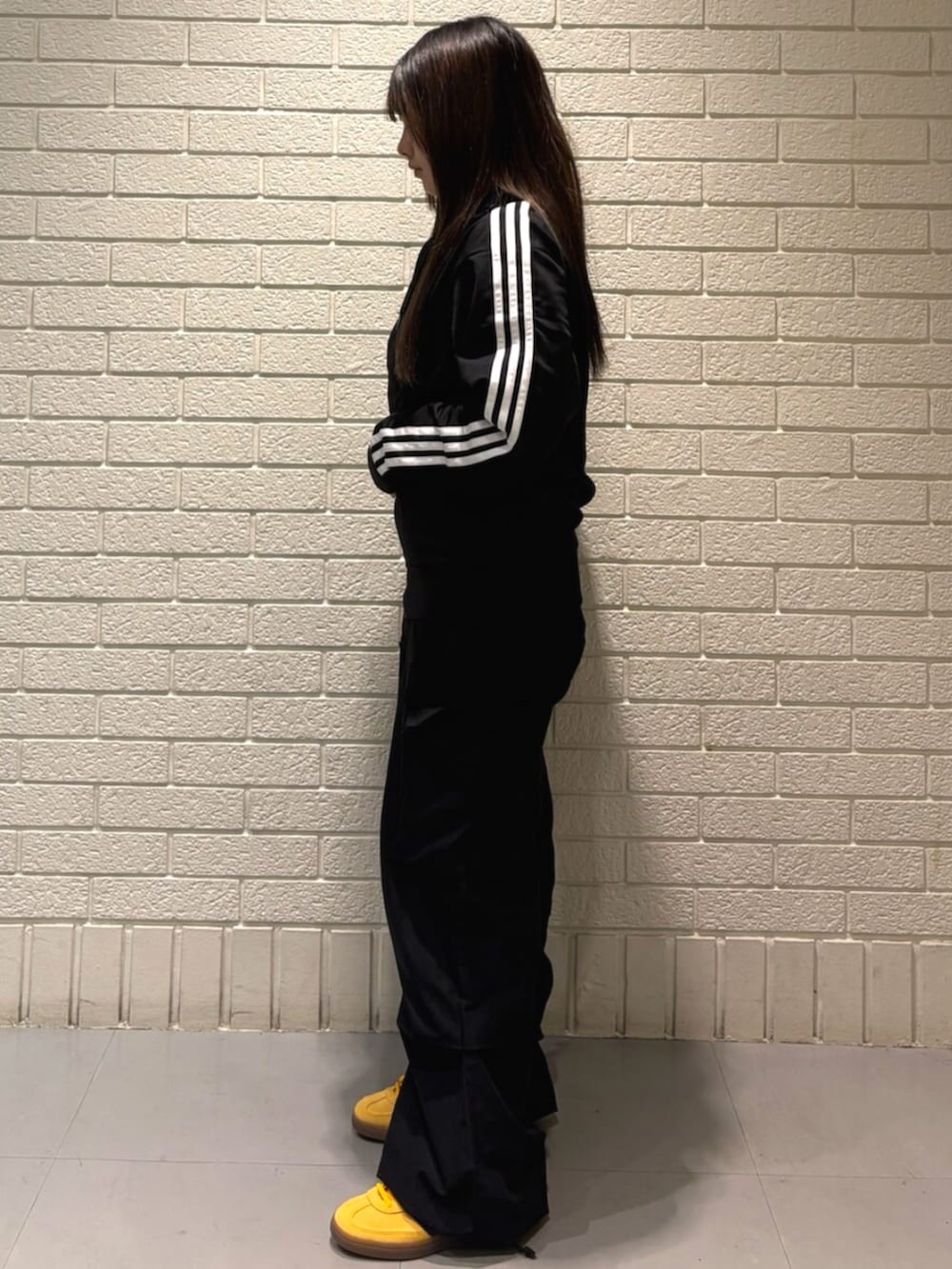 ブラック系のトップス、イエロー系のスニーカーを着用したレディースの秋コーディネートの2枚目の写真