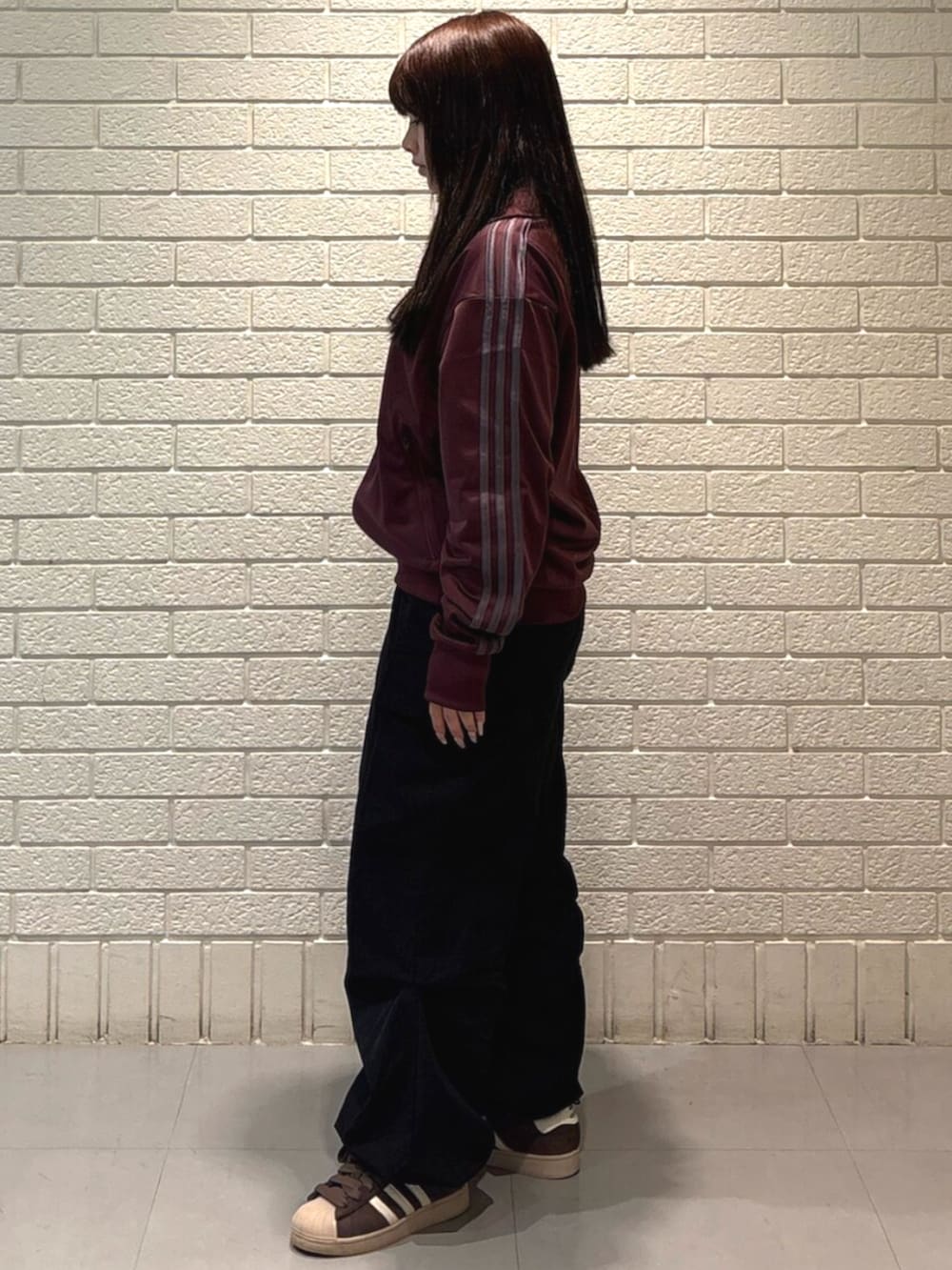 ブラウン系のスニーカー、レッド系のトップスを着用したレディースの春コーディネートの2枚目の写真