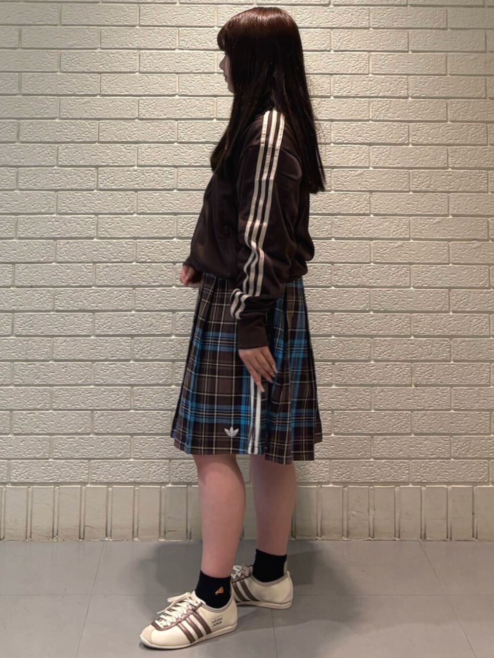 ブラウン系のスカート、ブラウン系のトップス、ホワイト系のスニーカーを着用したレディースの春コーディネートの2枚目の写真